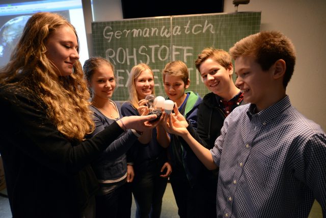 Eine Gruppe von jungen Menschen halten Energiesparlampen in der Hand.