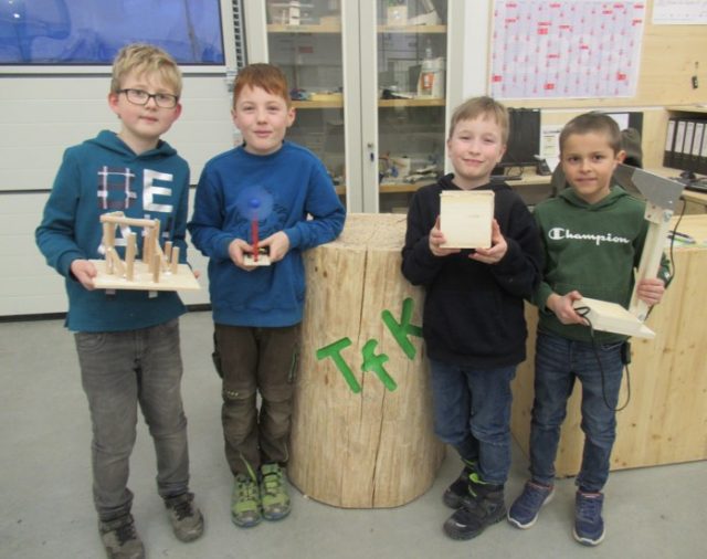 Vier Kinder präsentieren Werkstücke aus Holz.