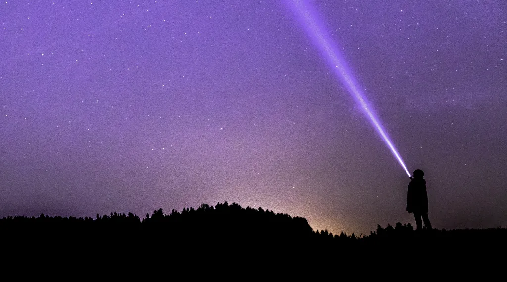 Eine Person leuchtet mit einer Taschenlampe in den Nachthimmel