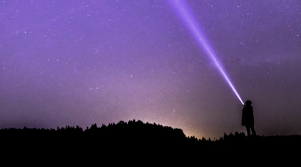 Ein Junge leuchtet mit einer Taschenlampe in den Nachthimmel
