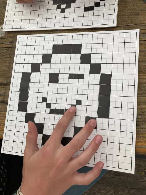 Smiley, gelegt aus schwarzen Quadraten auf einem Gitternetz