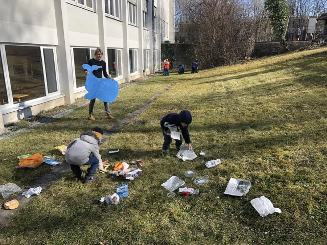 Kinder sammeln Müll auf Grünfläche