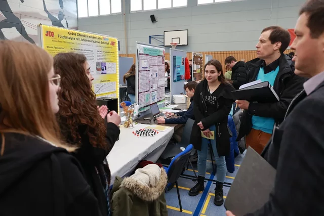 Schüler präsentieren wissenschaftliche Projekte in einer Turnhalle.