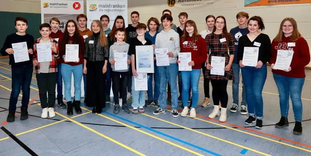 Junge Menschen halten Urkunden in der Hand und stehen zusammen für ein Gruppenbild