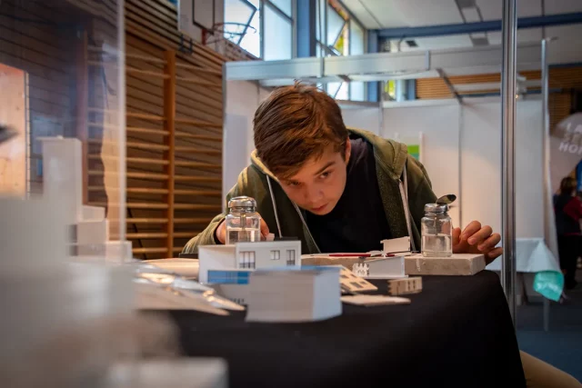 ein Junge betrachtet konzentriet eine Kostruktion mit einem mit Wasser befüllten Salzstreuer