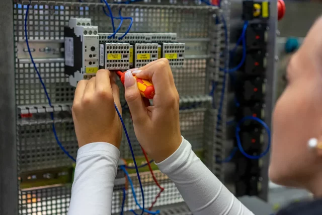 Person arbeitet an einem elektrischen Verteilerkasten.