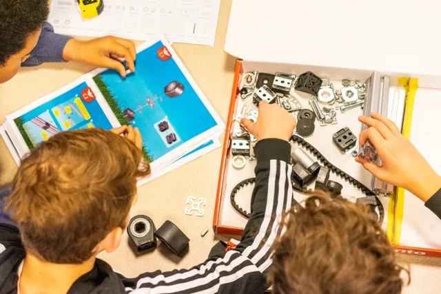 Kinder bauen aus vielen Einzelteilen etwas und folgen dabei einer Anleitung