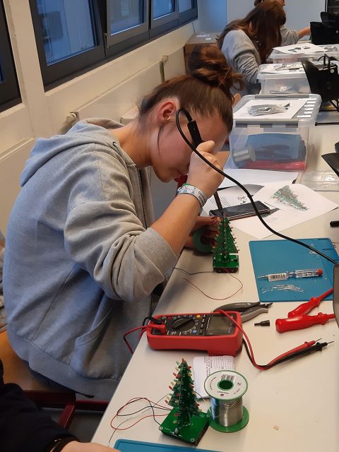 eine junge Frau arbeitet an einem kleinen Weinnachtsbaum mit LEDs