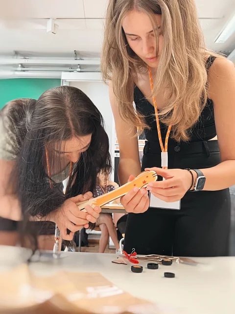 zwei junge Frauen bauen ein kleines Rennauto aus Holz