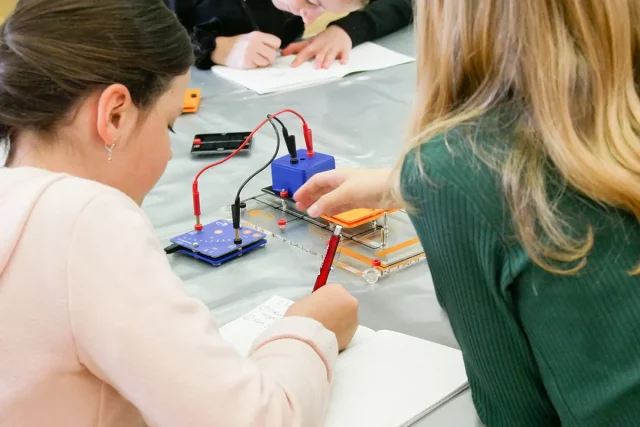 Kinder arbeiten an einem Tisch mit Spannungsregulator