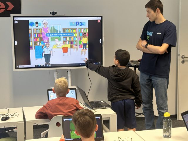 Kinder in einem Programmierkurs mit Lehrer am Whiteboard.