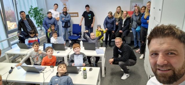 Gruppe von Kindern und Mentoren bei einem Programmierworkshop.