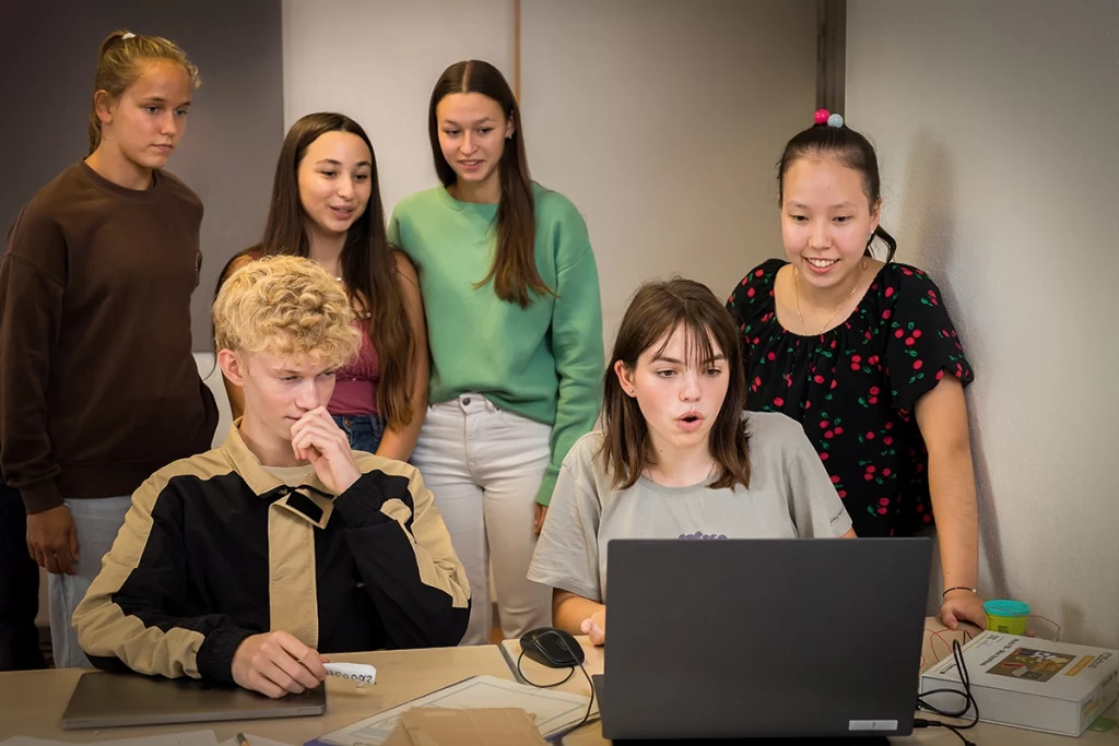 junge Menschen schauen gespannt auf Laptop