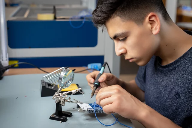 junger Mann lötet Kabel an eine Platine