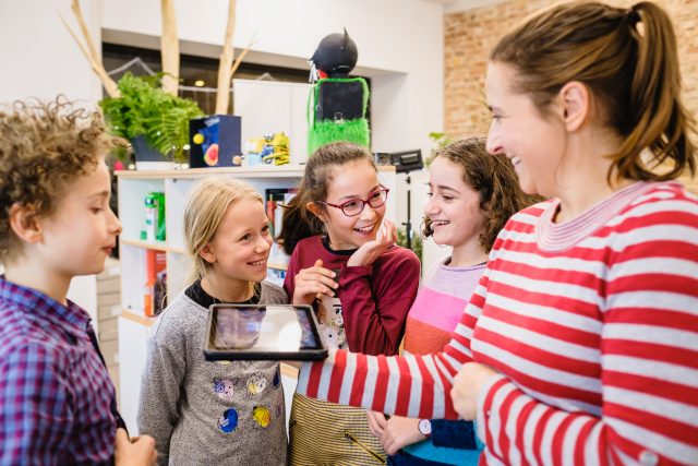 Kindergruppe sieht Tablet an.