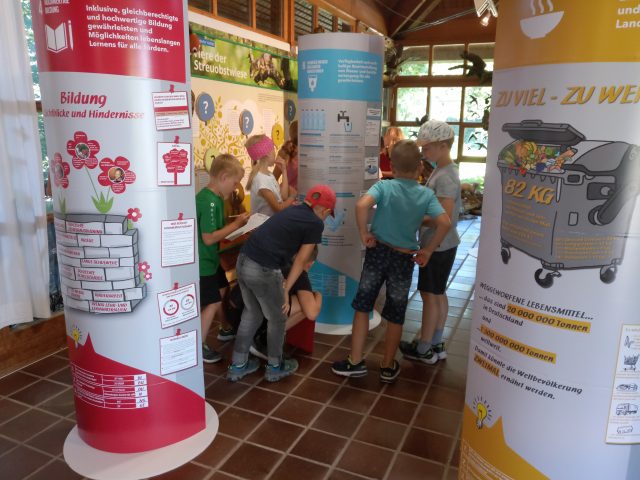 Kindergruppe um Ausstellungssäulen im Museum.
