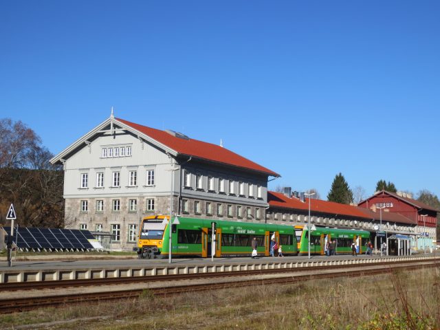 Zug am Bahnhof mit rotem Dach bei klarem Himmel.