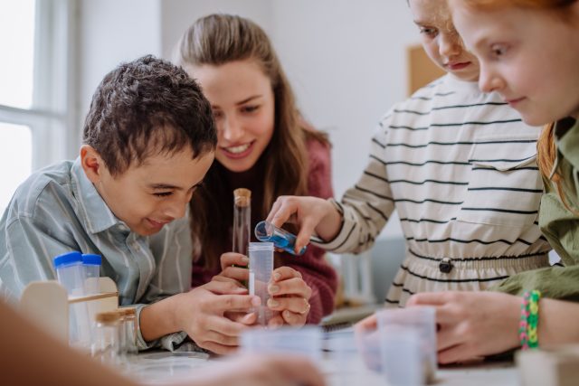 Kinder beim Chemieexperiment mit Reagenzgläsern.