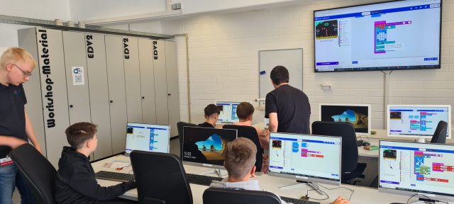 Jugendliche arbeiten an Computern in einem Technologieklassenraum.