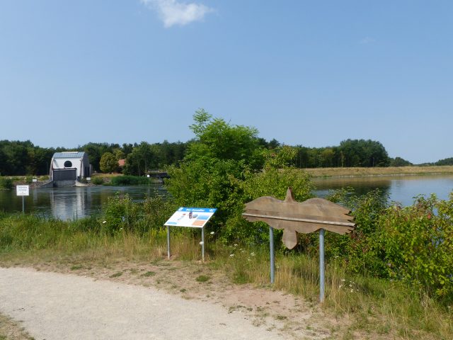 Landschaftsbild See mit Tafeln und Bootshaus