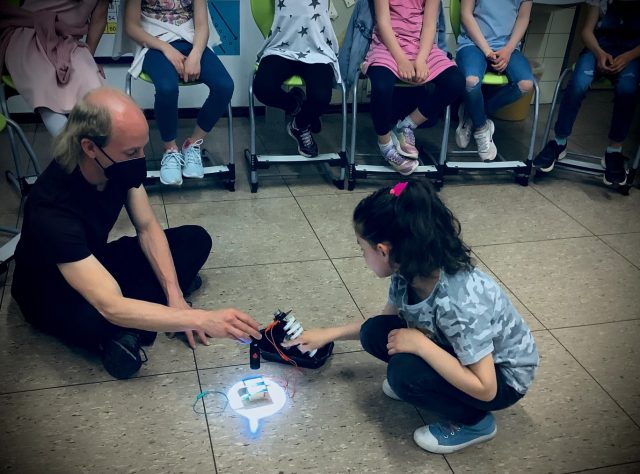 Gruppe von Kindern lernt mit einem Roboter