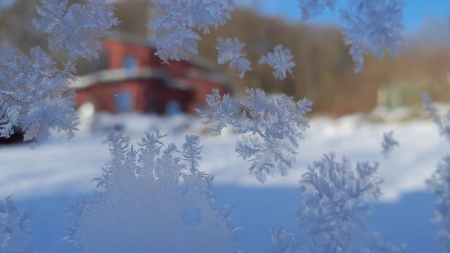 Eiskristalle mit einer verschneiten Hutte im Hintergrund.