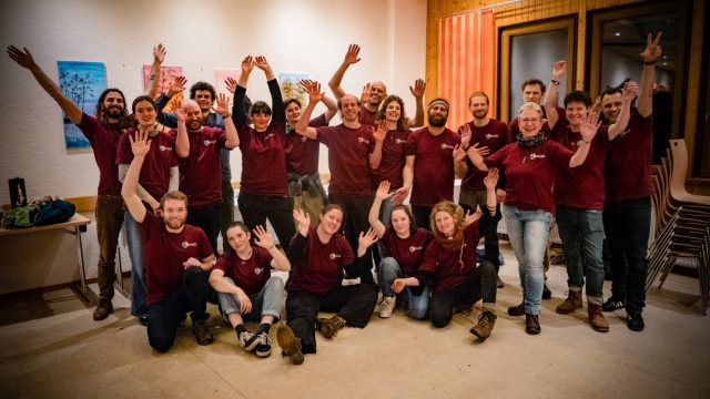 Gruppenfoto mit jubelnden Personen in einheitlichen Shirts.