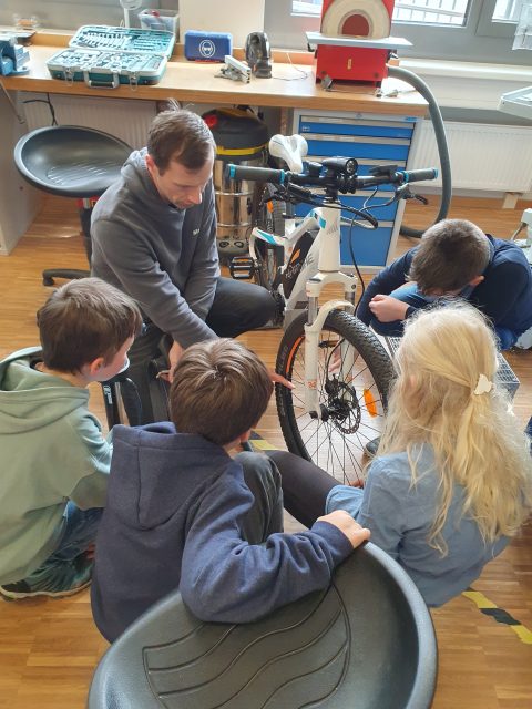 Kinder gruppieren sich um ein Fahrrad und lernen dessen Reparatur.