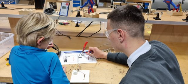 Zwei Personen basteln an einem elektronischen Projekt.