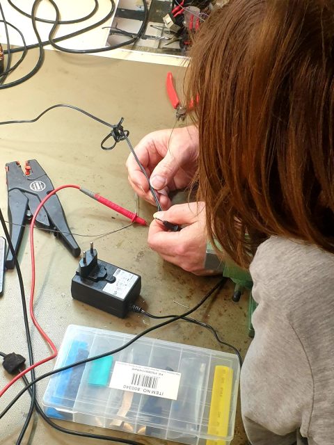 Person repariert elektronische Bauteile an einem Tisch