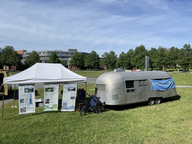 Wohnwagen und Zelt auf einer grünen Wiese im Freien.
