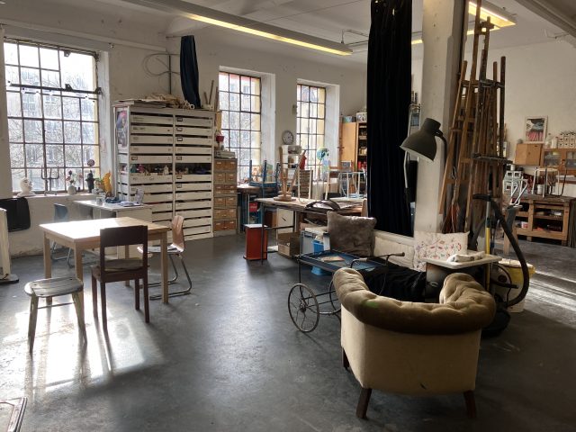 Ein geräumiges Künstleratelier mit Tischen und Kunstmaterialien.