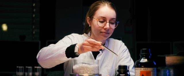 Person im weißen Kittel mit Laborinstrumenten.