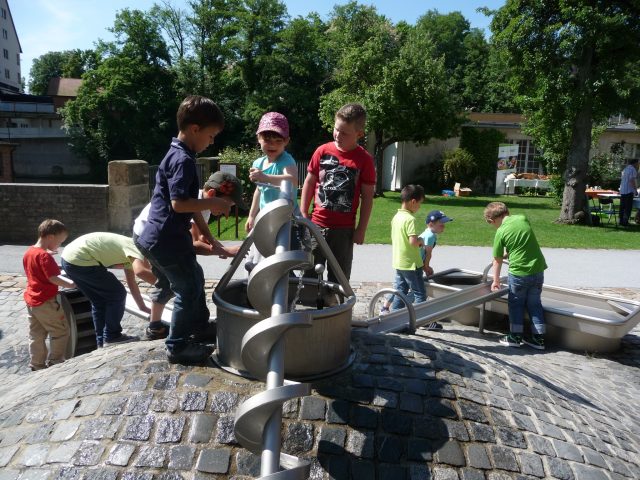 Kinder am Wasserspielplatz mit Wasserpumpe.
