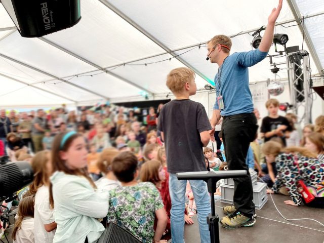 Moderator präsentiert im Zelt vor Kindern.