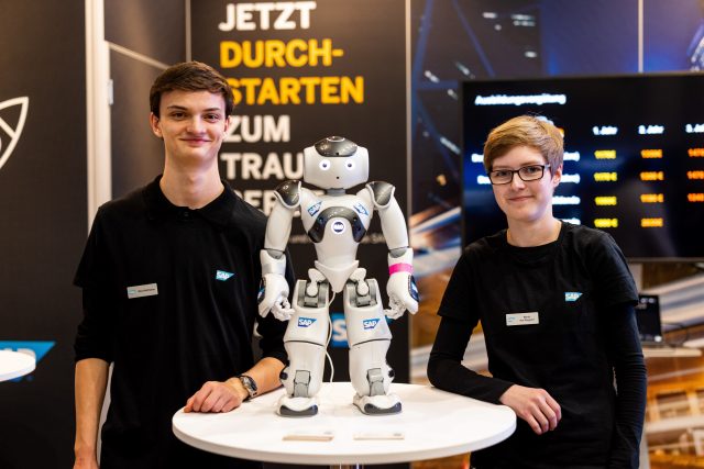 Zwei Menschen mit einem Roboter auf einem Tisch