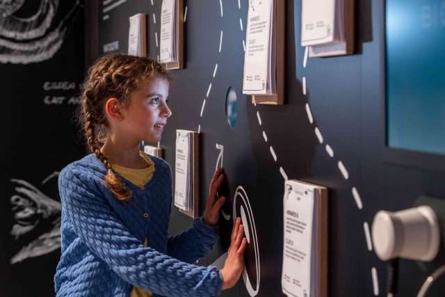 Kind am interaktiven Display mit Karten