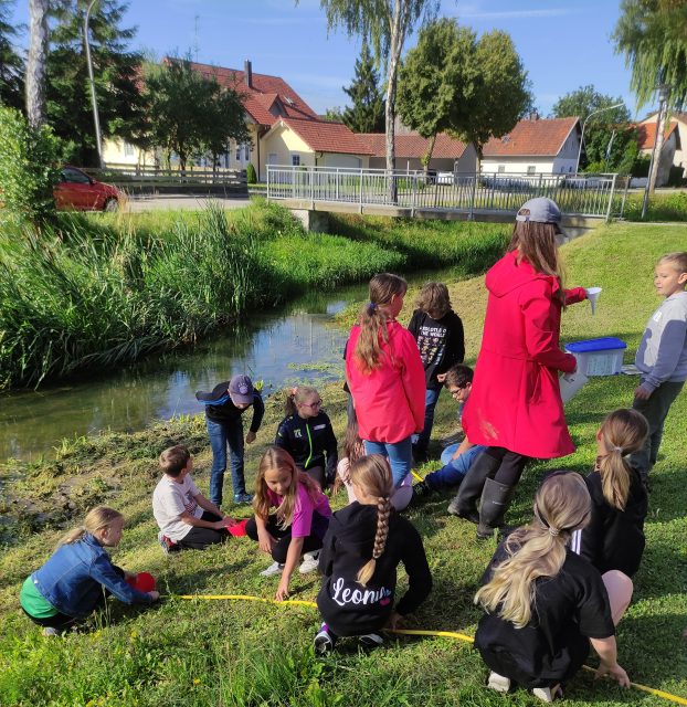 Kinder spielen und lernen am Flussufer