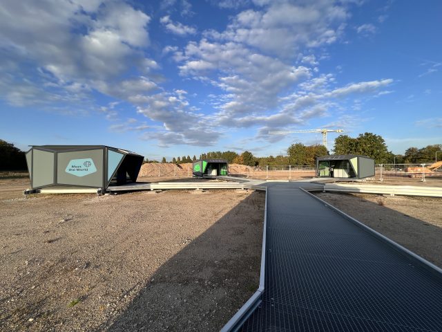 Drei Container eines solarbetriebenen Rechenzentrums ueber einer Kiesfläche