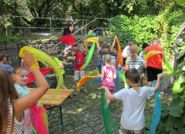Kinder spielen draußen mit bunten Tüchern