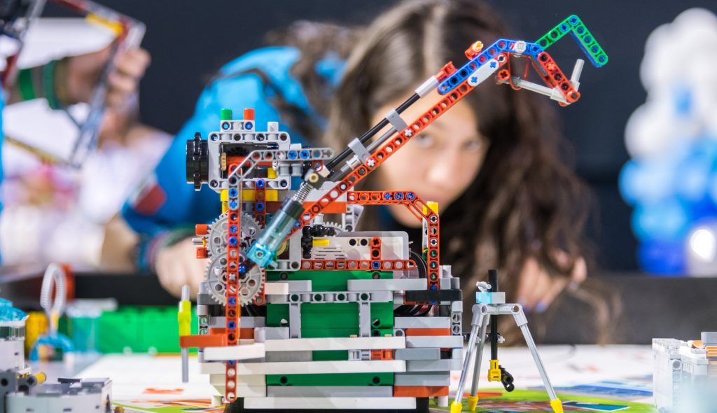Kind baut Lego Roboter Modell.