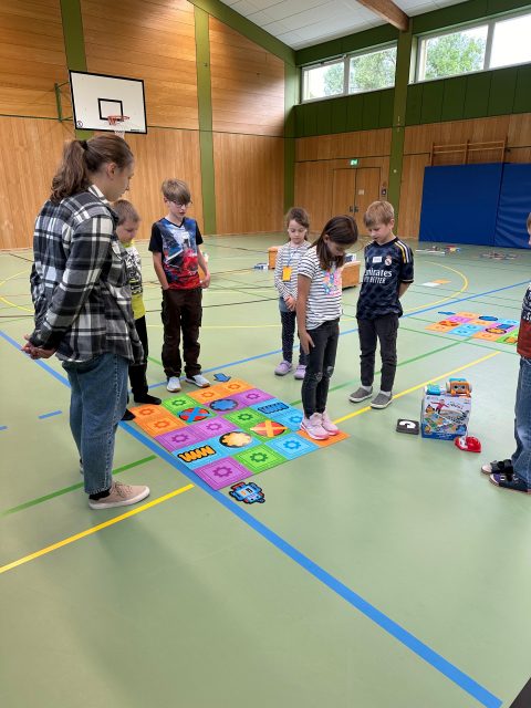 Kinder in einer Turnhalle mit buntem Bodenspiel