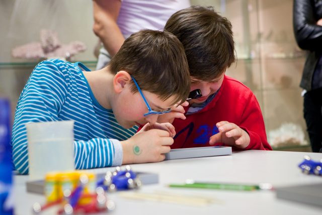 Zwei Kinder erforschen etwas mit einer Lupe