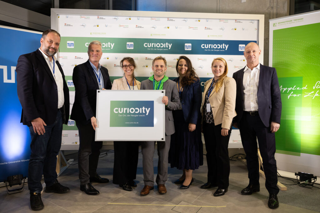Gruppe posiert vor Curocity Banner