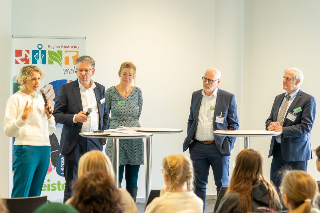 Vier Personen an Stehtischen in einer Diskussion.