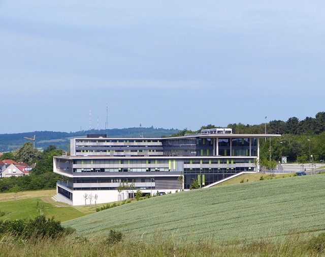 Modernes Gebäude auf einem Hügel vor blauem Himmel