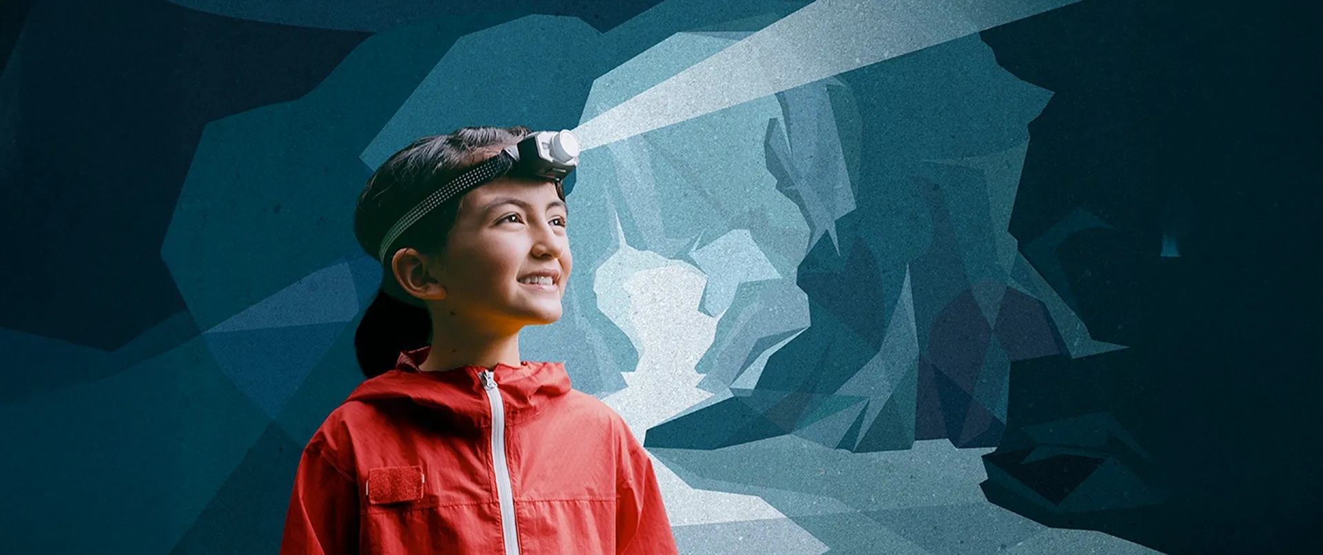 Kind mit Stirnlampe vor einer Höhle