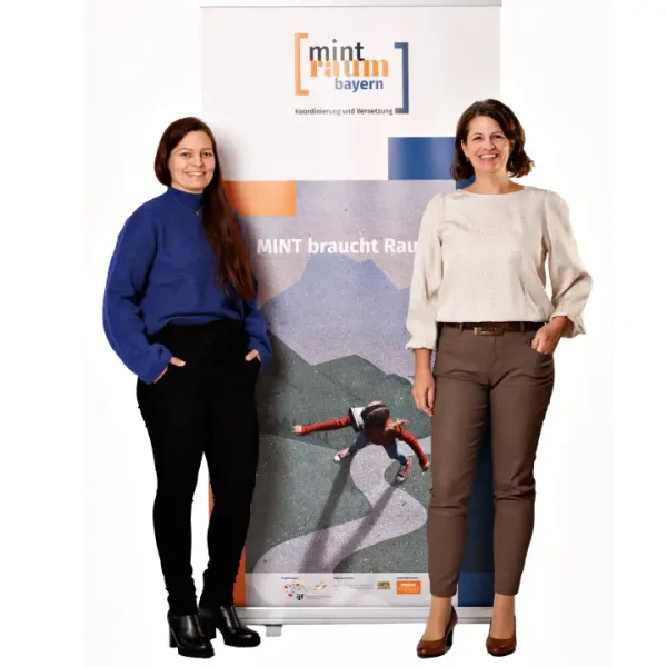 Petra Scheuermayer und Susanne Knotzer stehen links bzw. rechts neben dem Rollup vom MINTraum bayern.